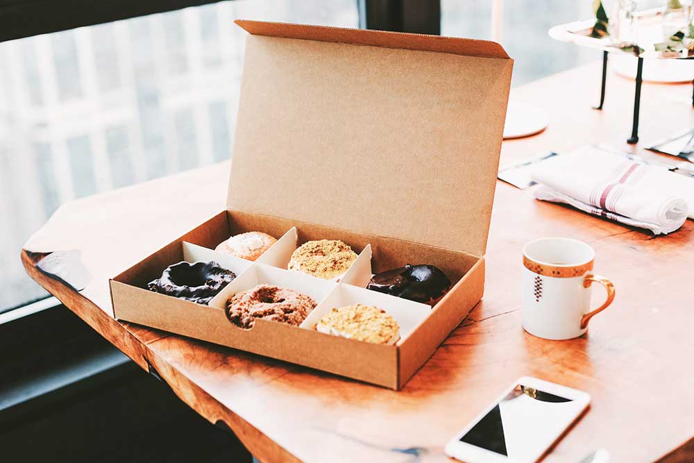 collide blog box of donuts on a table with mug of coffee