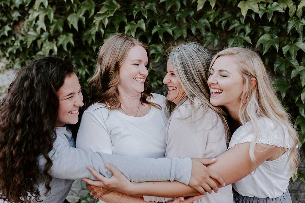 four women in a group hug smiling and joyful