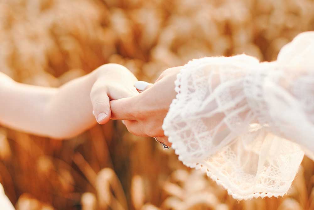 Two hands grasping one another in a field of wheat