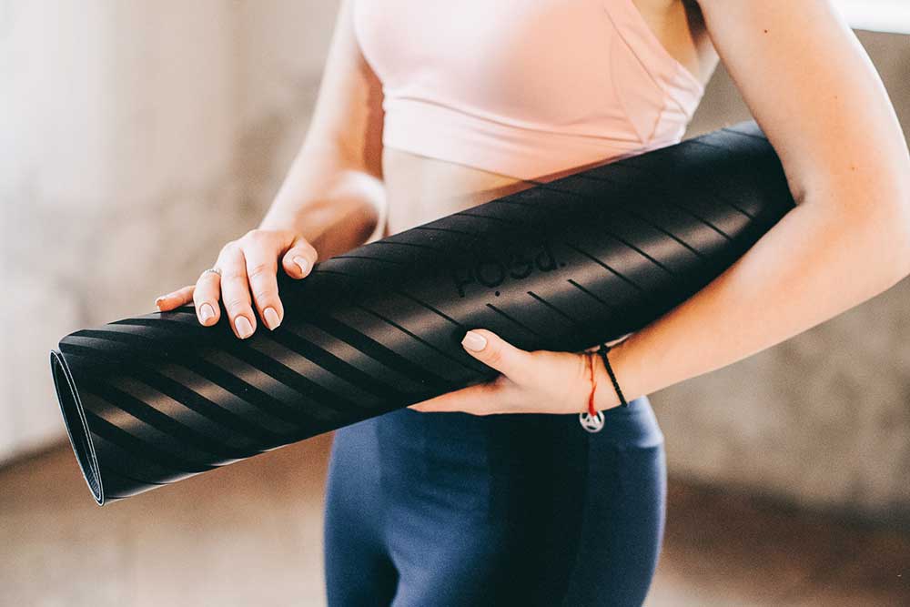 Woman holding a rolled up yoga mat