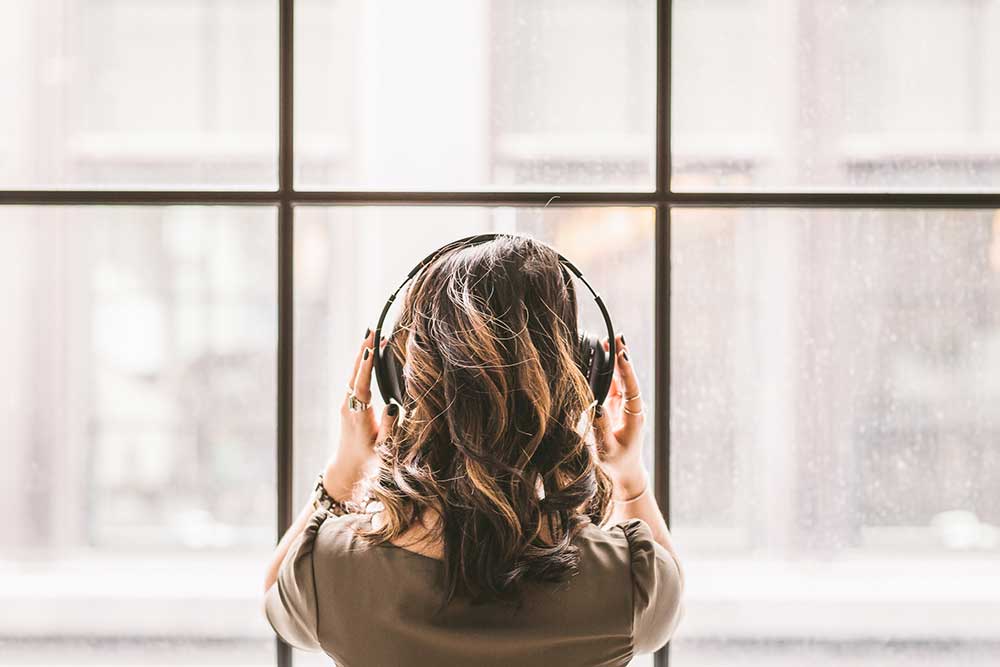 girl looking out window with headphones on