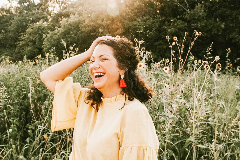 Brooke Sailer smiling in a field wearing a yellow shirt