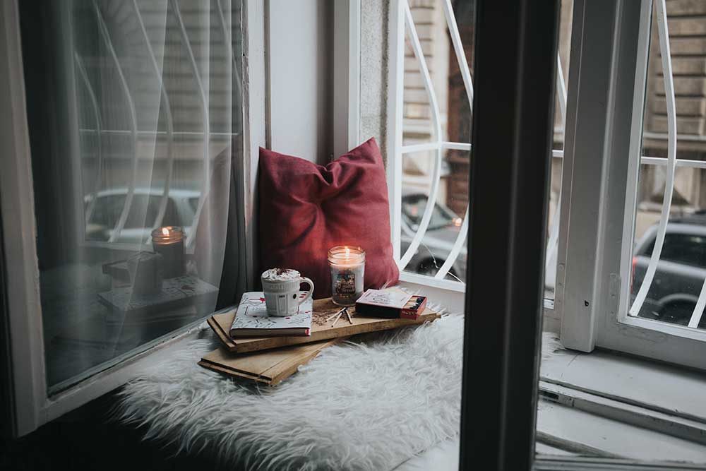 Collide blog cozy corner for stillness and devotions by the window with a red pillow and lit candle