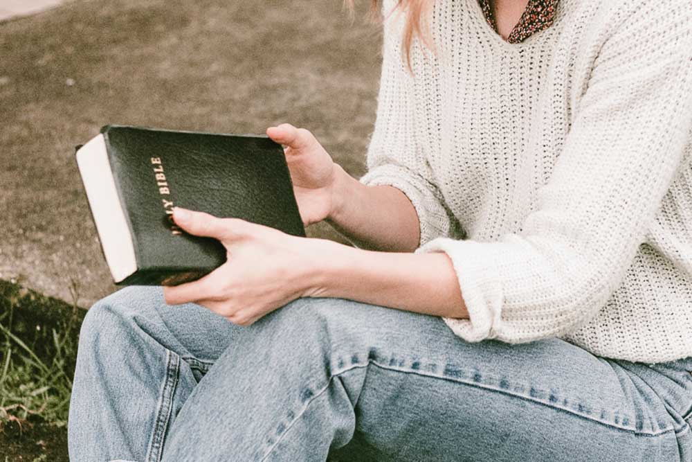Woman sitting on a step holding her Bible
