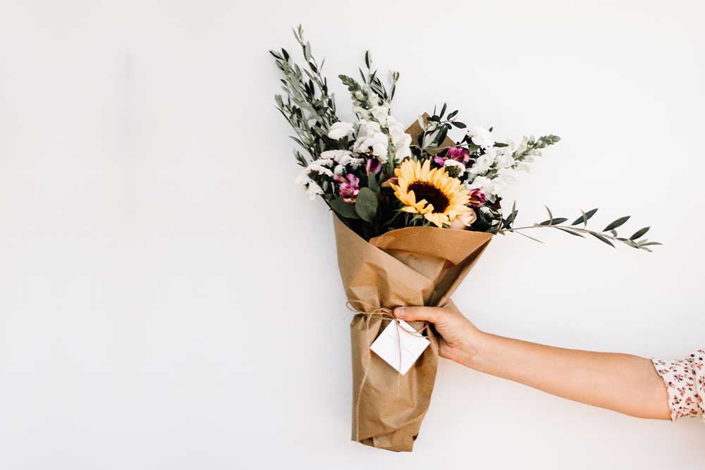 Collide Blog woman handing a bouquet of flowers