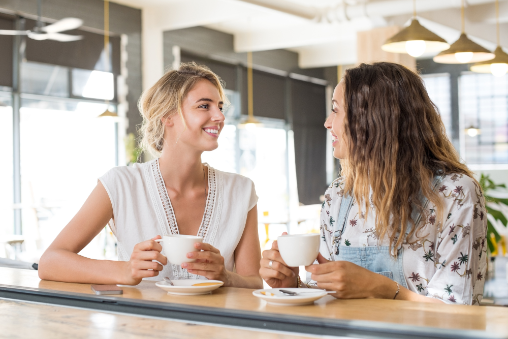 women facing each other smiling in a coffee shop
