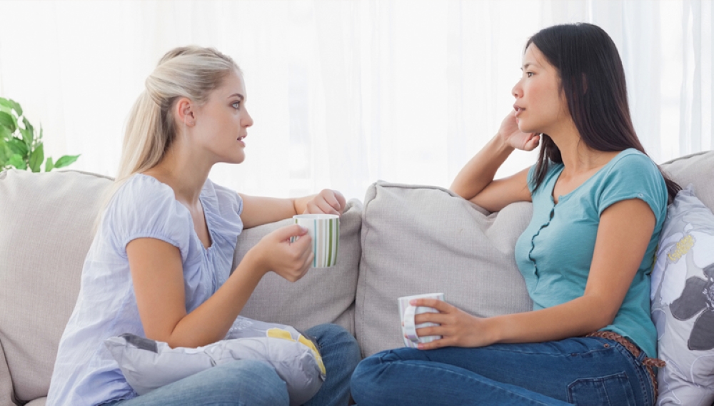 Two women sitting on a couch having a conversation