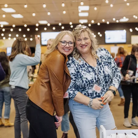 Two women hugging and smiling at Collide Conference.